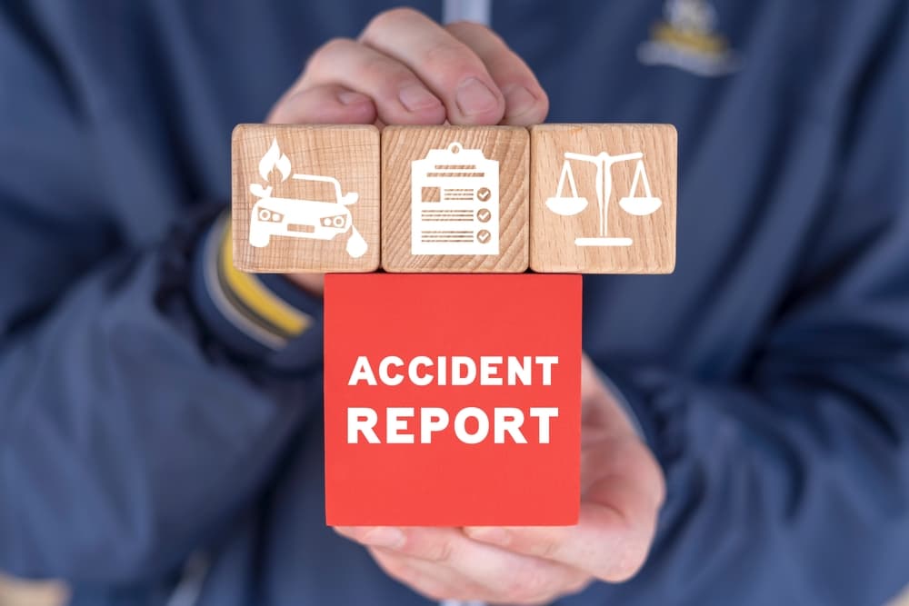 A businessman holding colorful blocks with the inscription "ACCIDENT REPORT." Concept of accident report, claim injury compensation, and filling out accident documentation.