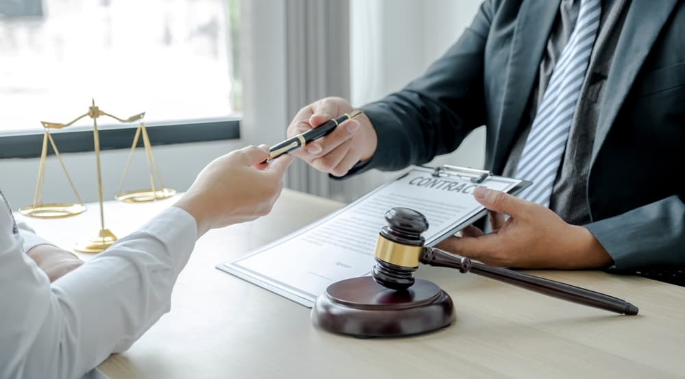 A lawyer, holding a pen, provides legal consultation on a business dispute at the office, with a justice scale and gavel present.