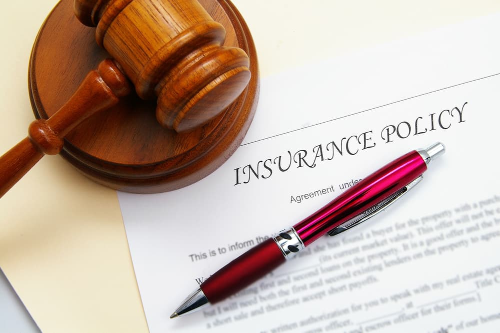 Insurance policy with a legal gavel and a pen.