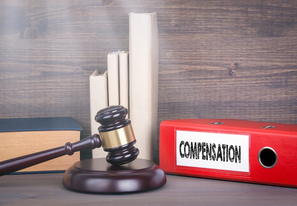 Compensation: A wooden gavel and books in the background symbolize law and justice.