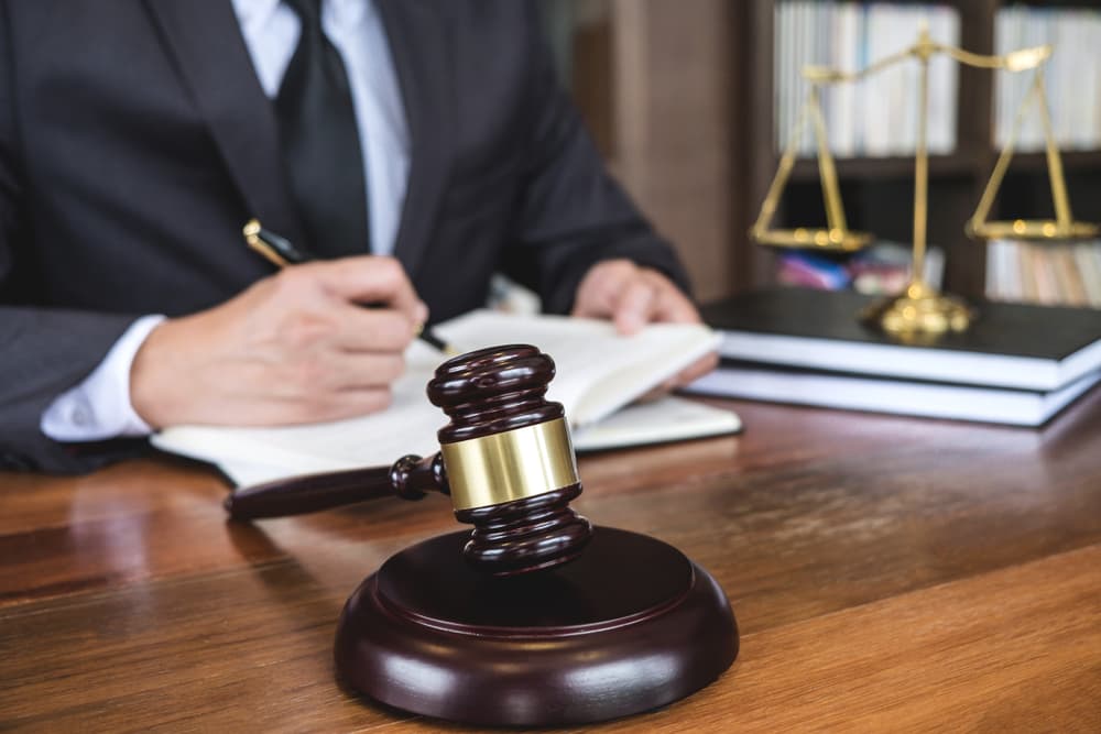 Legal law, advice, and justice concept: A judge's gavel with justice lawyers and a counselor in a suit working on documents in a courtroom.