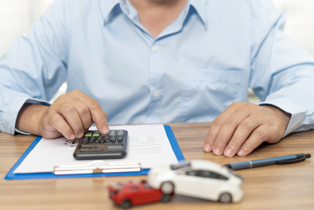 A man use calculator on table To calculate the damage from a car accident