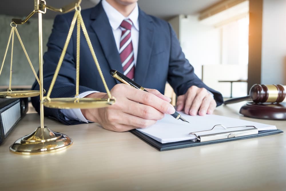 A lawyer's hand carefully writes a legal document in court, symbolizing justice and law.