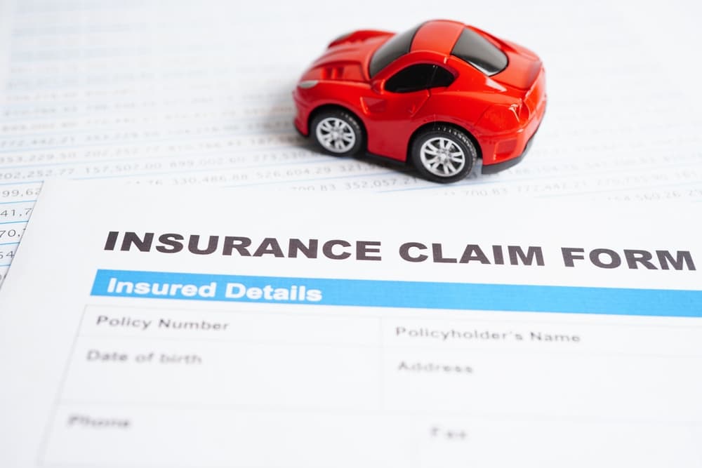 A stethoscope placed on an insurance claim form for a car accident, symbolizing the examination of car loans, insurance, and leasing concepts in the automotive finance industry.