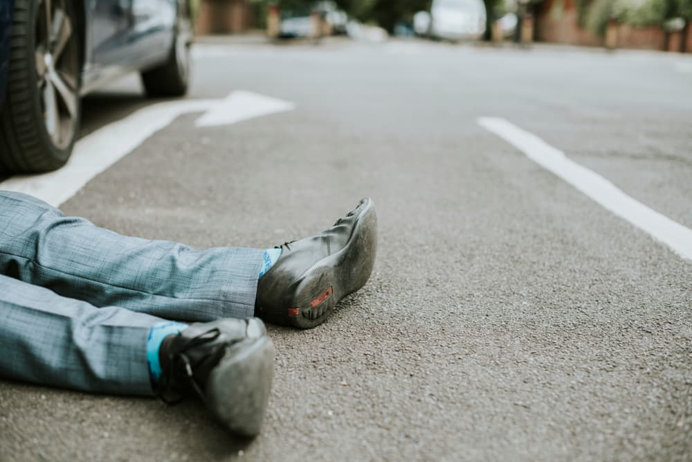 Individual lying on the ground after a hit-and-run car accident.