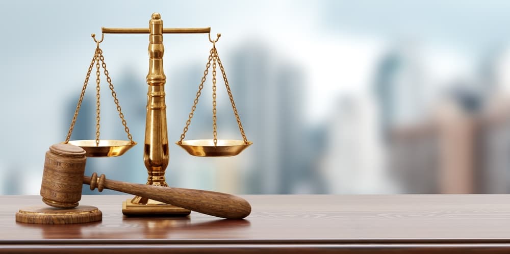 A set of legal scales balances next to a judge’s gavel, symbolizing justice and fairness.