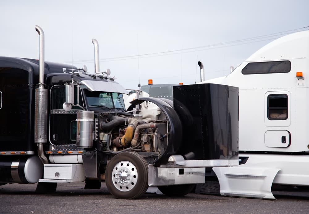 A large black classic big rig semi truck with its hood open is undergoing a technical inspection of the engine to ensure everything is in working order.