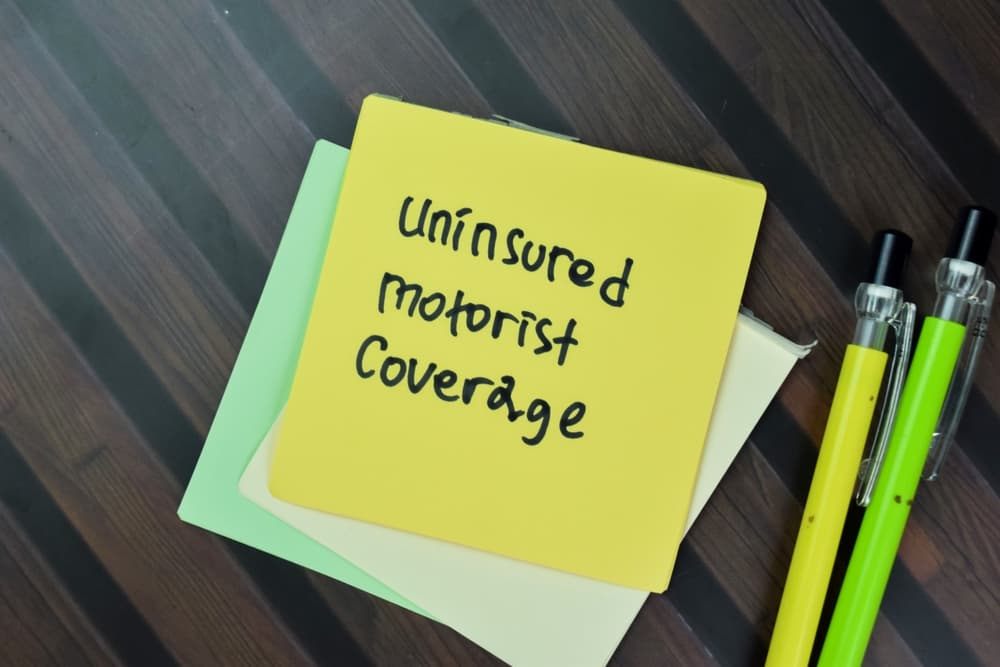 The concept of Uninsured Motorist Coverage written on sticky notes and placed on a wooden table.