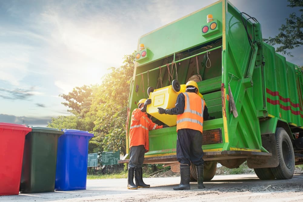 Men who dispose of rubbish in garbage truck that works for public benefit, empty trash container