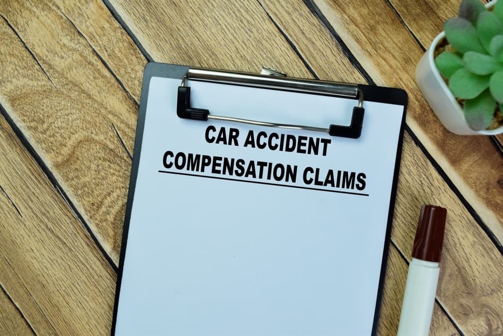 Car Accident Compensation Claims write on paperwork isolated on Wooden Table.