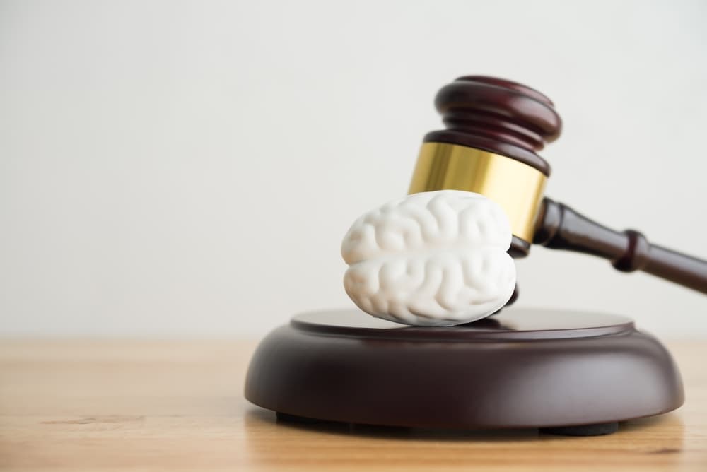 Brain and hammer judge gavel on wooden table in courtroom 