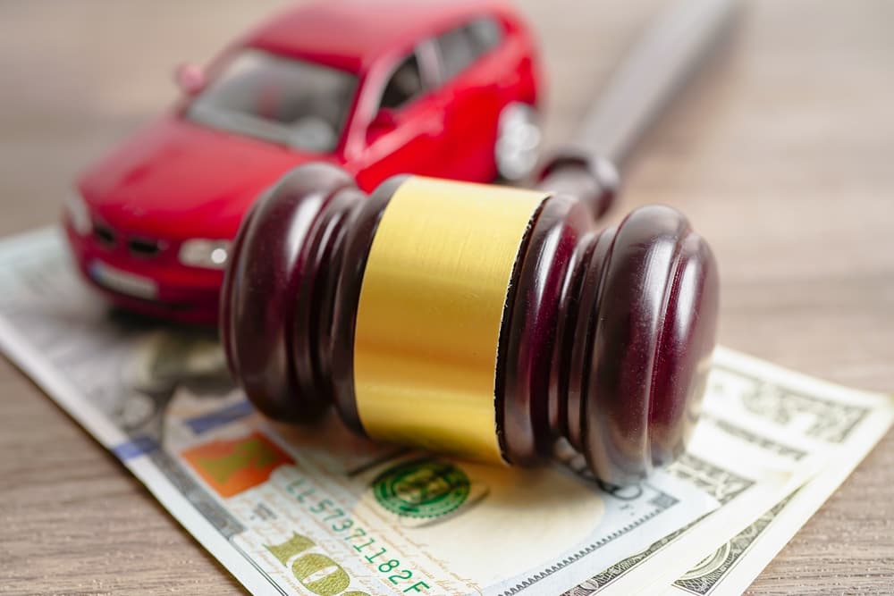 Gavel for judge lawyer with car on US dollar money banknotes.